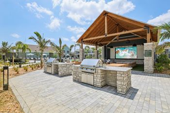 A patio with a stone table and a wooden roofed pavilion.
